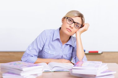 Young teacher surrounded with assignments.