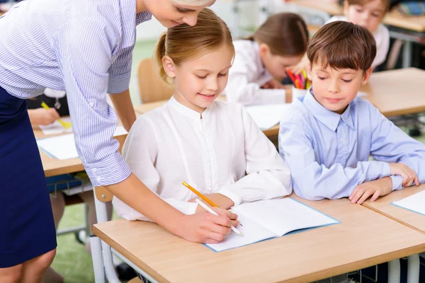 Professora e seu aluno estão escrevendo juntos . — Fotografia de Stock