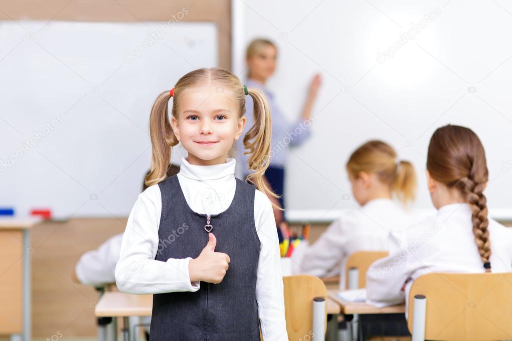 Little cute pupil is showing thumbs up.