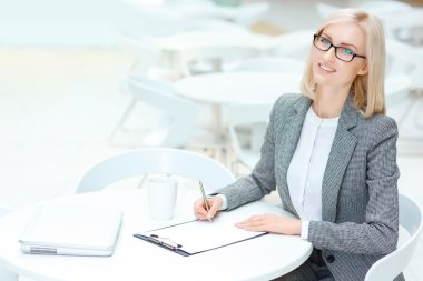 Pretty business woman signing papers