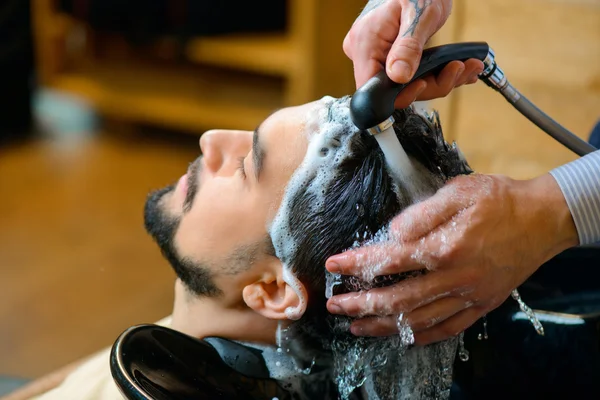 Professional barber washing hair of the client — Zdjęcie stockowe