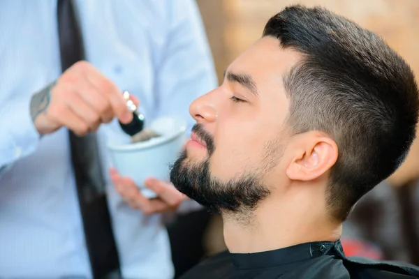 Peluquero profesional afeitando la barba de su cliente — Foto de Stock