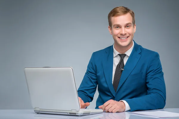 Lächelnder Nachrichtensprecher, der mit seinem Laptop arbeitet. — Stockfoto