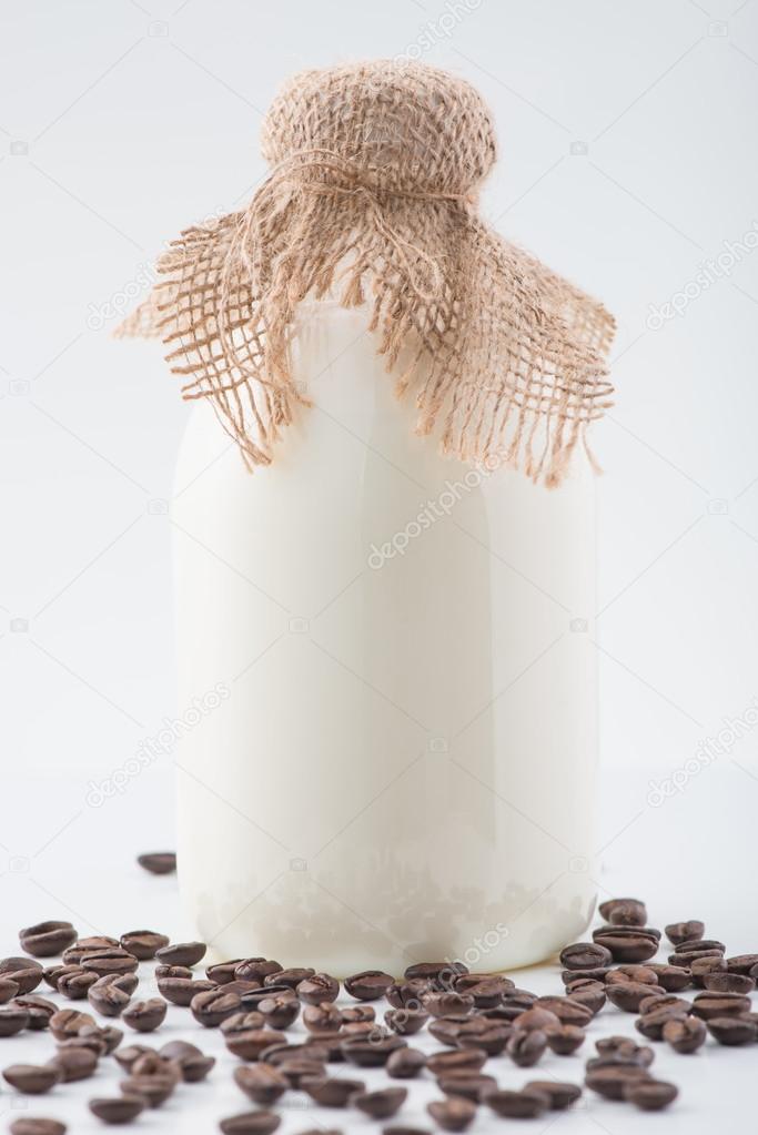 Glass bottleful of milk and coffee beans.