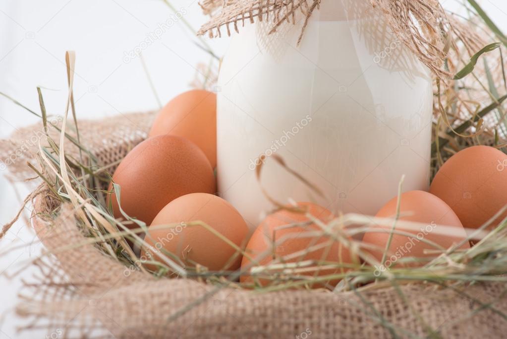 Bottle of milk and eggs in straw nest.