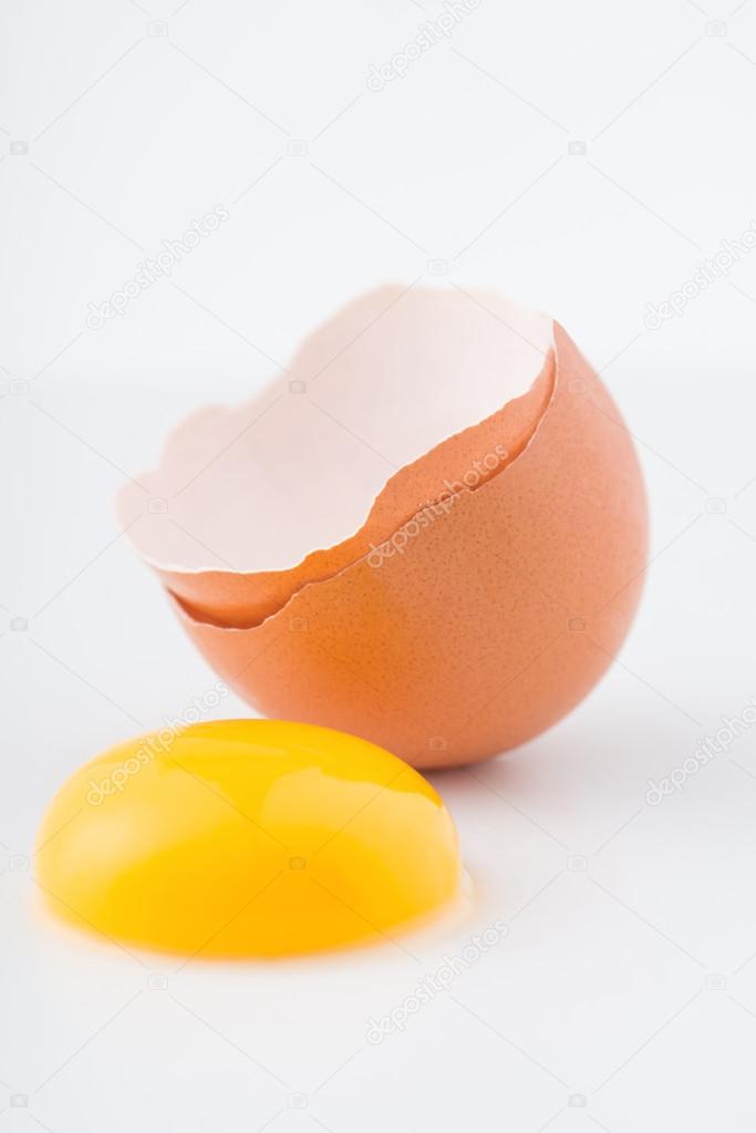 Eggshell with yolk outside of it on the surface.