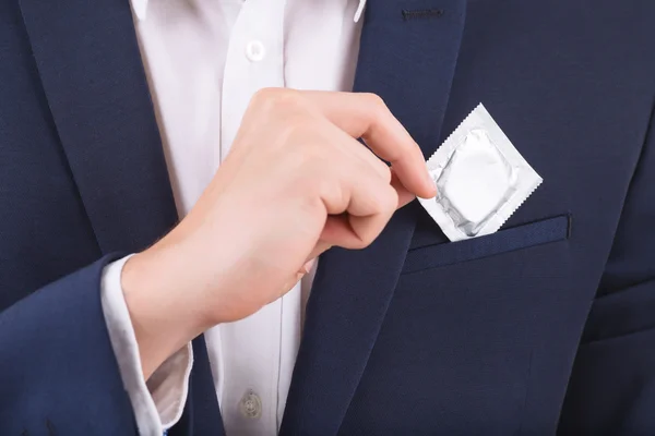 Mano masculina poniendo condón en el bolsillo del pecho . — Foto de Stock