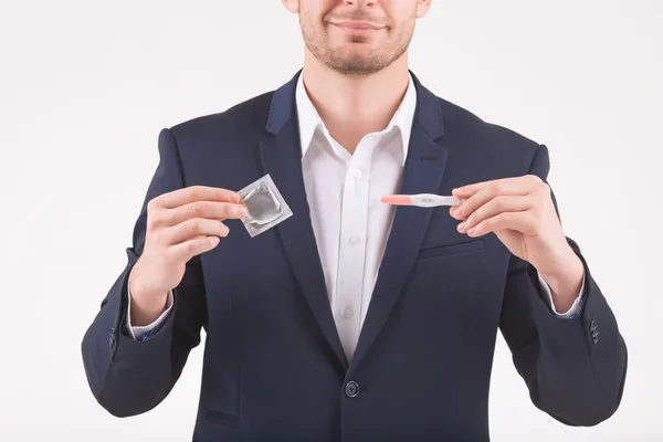 Hombre que sostiene el condón y la prueba de embarazo . —  Fotos de Stock