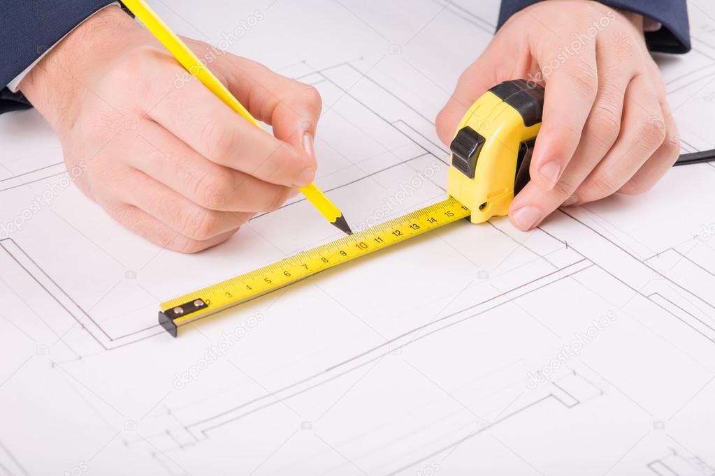 Male hands drawing a building plan.