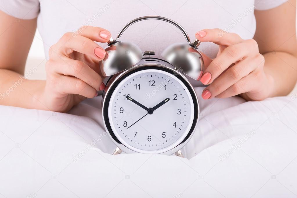 Female hands and alarm clock