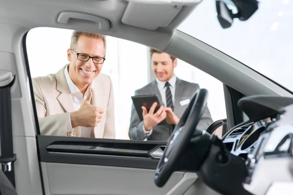 Assistente di vendita che mostra auto al cliente — Foto Stock