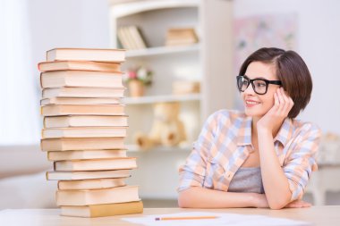 Yığın kitap önünde oturan genç kız.