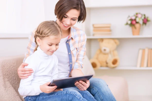 Dziewczynka i jej mama są za pomocą tabletu. — Zdjęcie stockowe