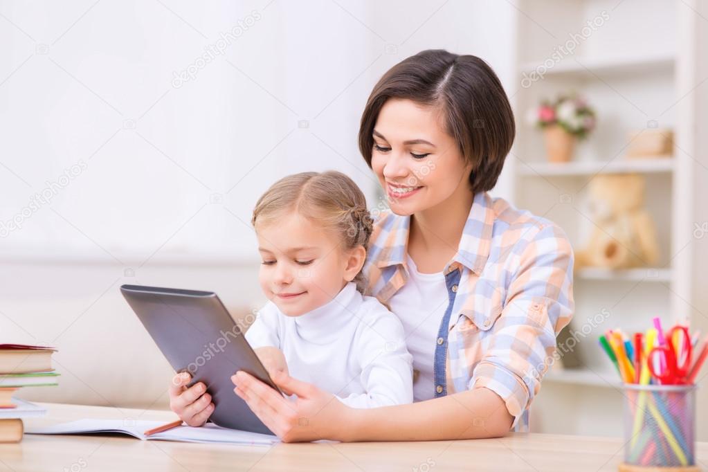 Mom and daughter are using portable tablet.