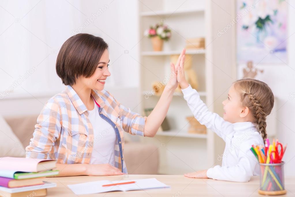 Mom and daughter are high-fiving each other.