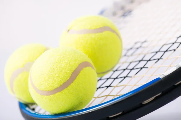 Tres pelotas de tenis y una raqueta . — Foto de Stock