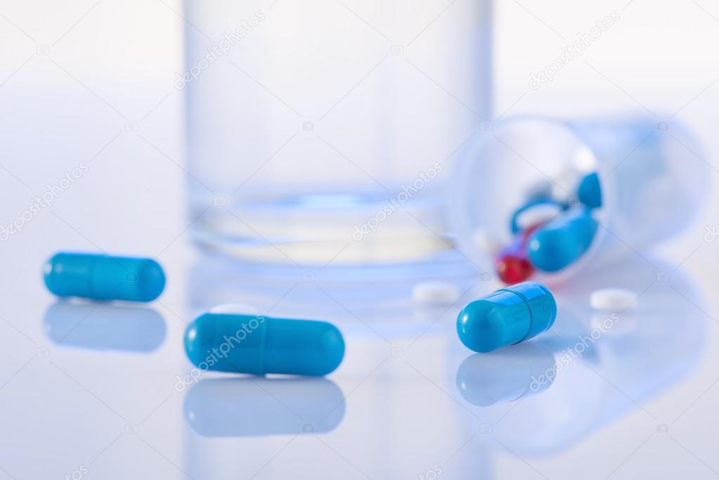 Pills and glass of water on the surface.