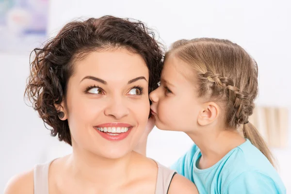 Tochter küsst ihre lächelnde Mutter. — Stockfoto