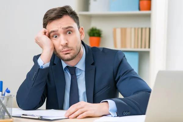 Emotional office worker sitting at the table — Stockfoto