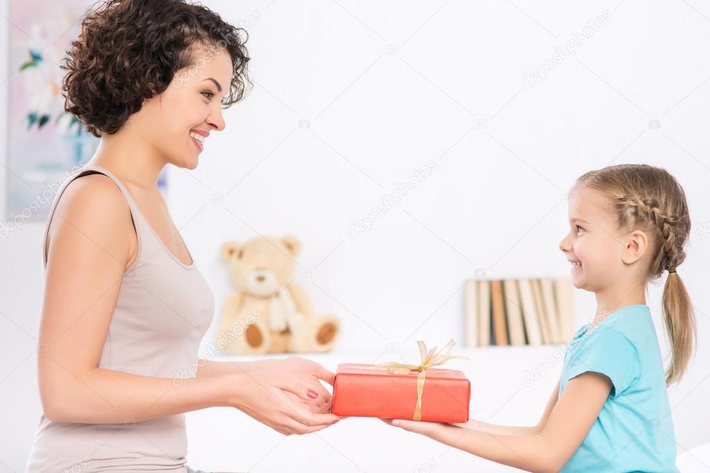 Little girl is giving her mom wrapped present.