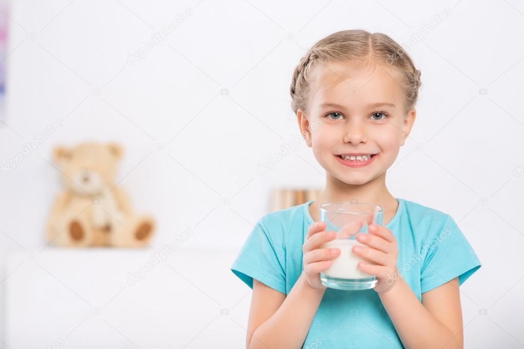 Smiling child is holding a glass of milk.
