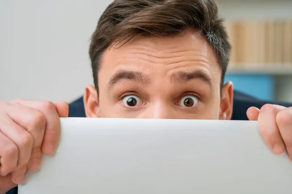 Pleasant office worker hiding behind laptop — Zdjęcie stockowe