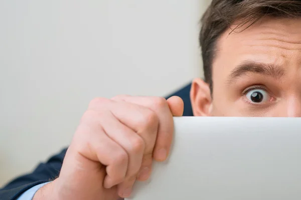 Pleasant office worker hiding behind laptop — Stockfoto
