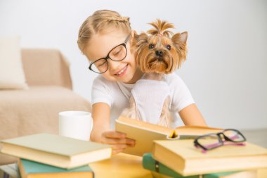 Küçük kız köpeğiyle okuyor.