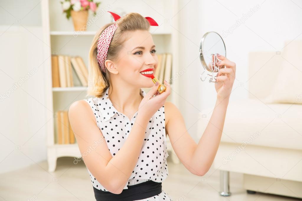 Young attractive girl putting lipstick on.