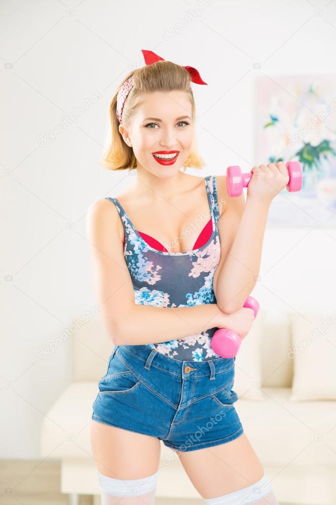 Young appealing woman upholding her dumbbells.