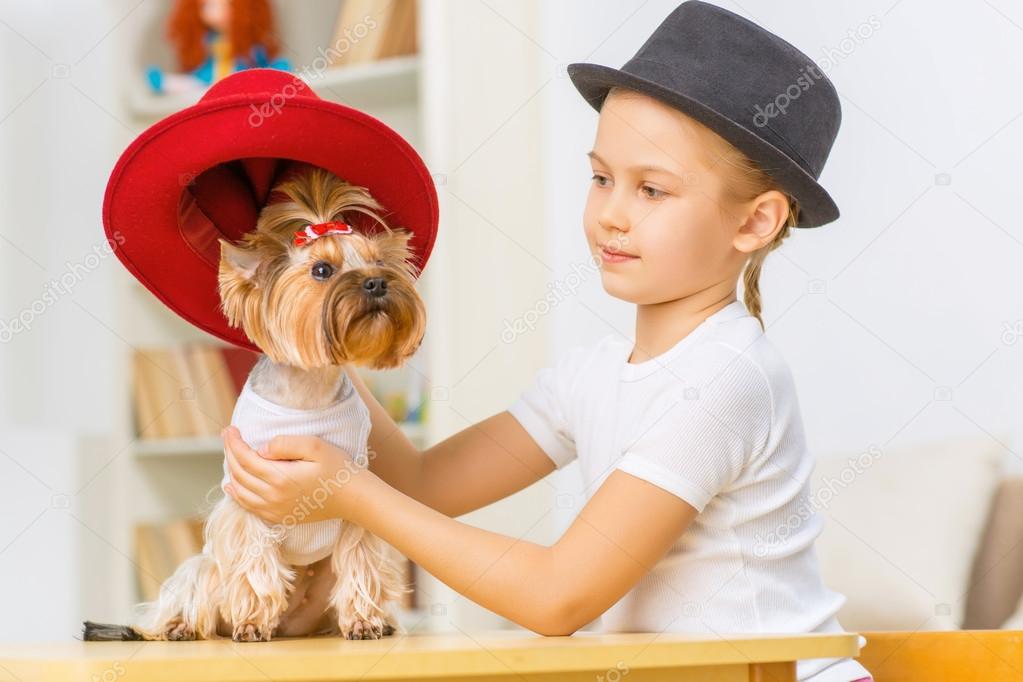 Little girl is dressing her dog up.