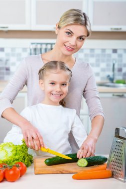 Anne ve kızı yemek yapıyor.