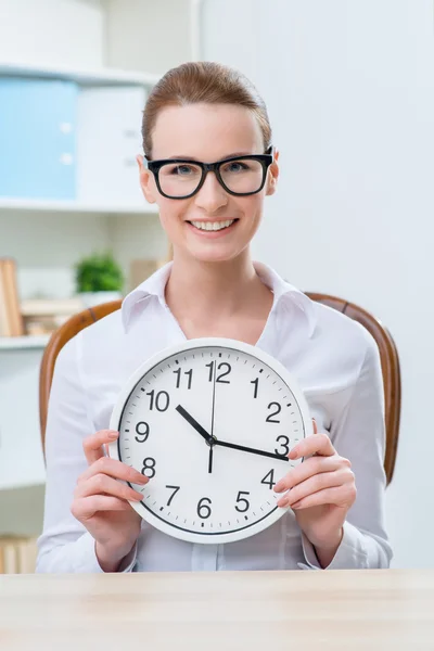 Mujer sonriente sosteniendo el reloj — Foto de Stock
