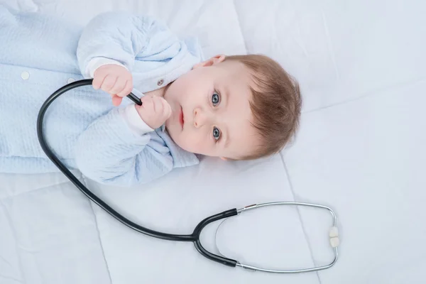 Cute infant child lying with stethoscope on the couch — Stock Photo, Image