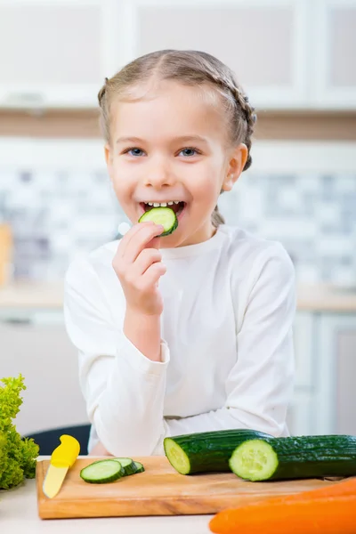 Trevlig liten flicka äter gurka — Stockfoto