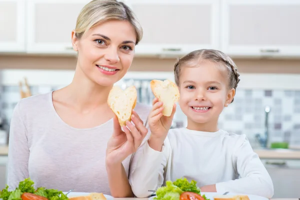 Mother and her daughter eating in the kitchen — Stock Photo, Image