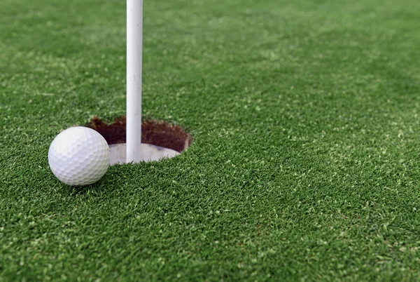 Golfboll och flaggstång av Manhärdat gräs av putting green — Stockfoto