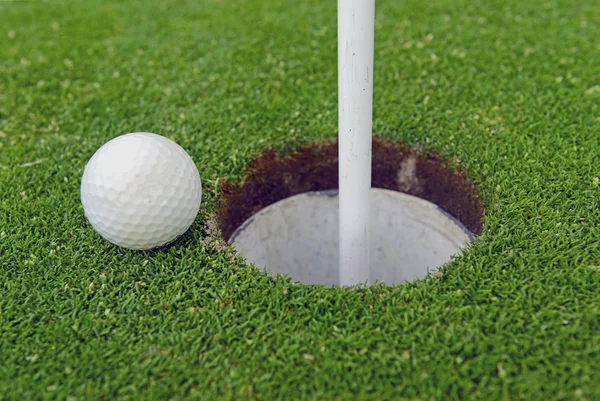 Golfboll och flaggstång av Manhärdat gräs av putting green — Stockfoto