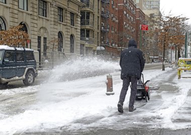 Resident with snowblower on street after snowstorm clipart