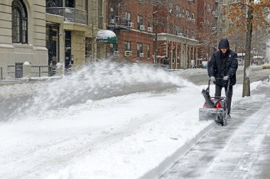 Resident with snowblower on street after snowstorm clipart