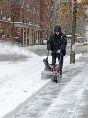 Resident with snowblower on street after snowstorm clipart