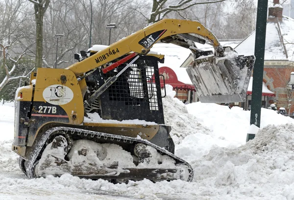 Будівельне устаткування прибирають сніг на вулиці після хуртовини — стокове фото