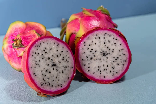 Pitaya fruits. Dragon fruit in halves. Blue background. Natural and refreshing food. Exotic fruit, rich in fibers.