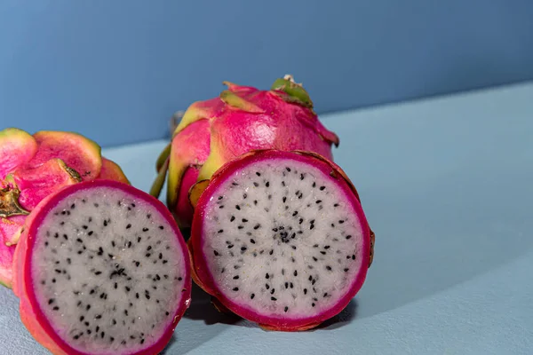 Pitaya fruits. Dragon fruit in halves. Blue background. Natural and refreshing food. Exotic fruit, rich in fibers.