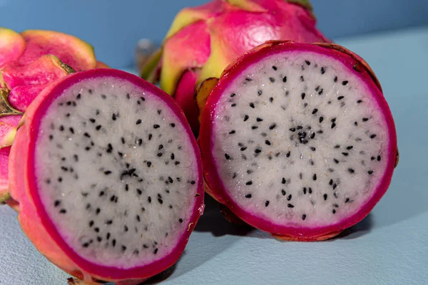 Pitaya fruits. Dragon fruit in halves. Blue background. Natural and refreshing food. Exotic fruit, rich in fibers.