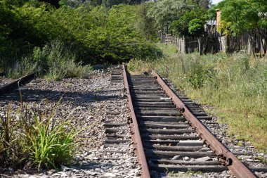 Eski demiryolu ve paslı raylar. Terk edilmiş tren istasyonu. Yazın doğal bir manzara. Tren taşıma altyapısı.