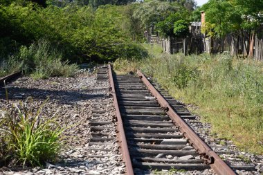 Eski demiryolu ve paslı raylar. Terk edilmiş tren istasyonu. Yazın doğal bir manzara. Tren taşıma altyapısı.