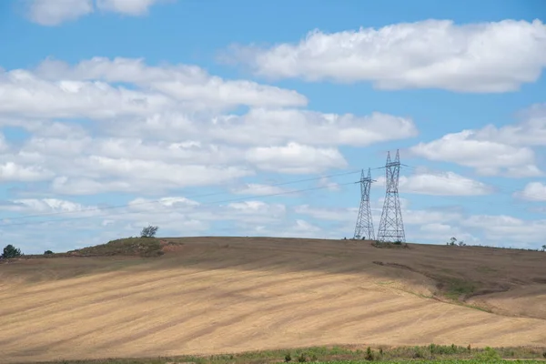 Power transmission towers. Electric transmission infrastructure. technology. Rural landscape. Agricultural production field. Blue horizon with clouds. Pampa biome in southern Brazil.