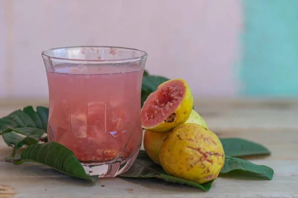 Glass of guava juice. Detox juice. Natural and refreshing drink. Guavas on wooden background. Exotic fruits. Fruit juice