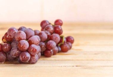 Bir demet pembe üzüm. Masa üzümleri tüketime hazır. Seçici odak noktasında ahşap arka plan. Meyve suyu ve reçel yapmak için meyve. Sarmaşık ürünü. Detoks meyveleri.